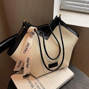 Dettaglio della borsa tote beige a pieghe con spalline nere e nastro di seta logato