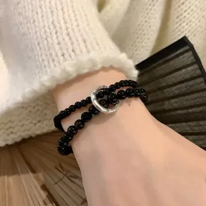 Detail of double-layer black beaded bracelet with engraved silver metal ring clasp