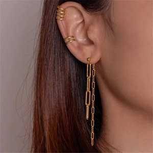 Close-up of golden multi-layer ear cuff and long chain drop earring on model ear