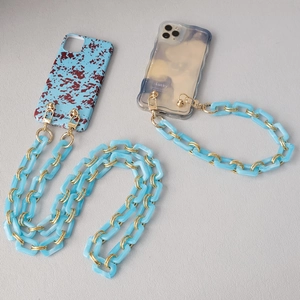 Close-up of wavy acrylic phone cases with thick light blue resin links and gold clasps