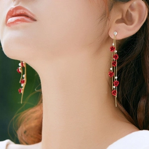 Elegant long red rose tassel earrings with shimmering rhinestones on a model's ear