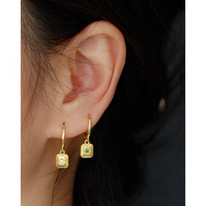 Detailed view of gold 925 silver starburst earrings with green and clear zircon stones