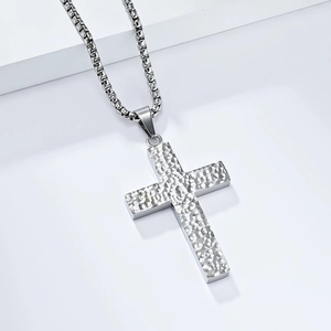 Détail d'un pendentif croix martelé en argent sur une chaîne box en acier inoxydable