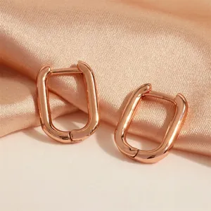 Detail of rose gold rectangular geometric earrings resting on elegant champagne silk fabric