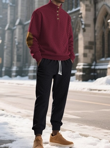 Detailed shot of burgundy half-zip knit sweater with contrast elbow patches and black pants