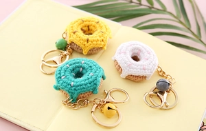 Three handmade crochet donut keychains in yellow green and white with colorful sprinkles