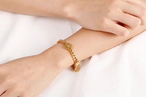 Close-up of golden stainless steel four-leaf clover bracelet on model wrist