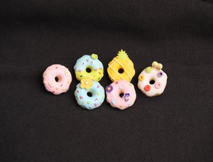 Close-up of six colorful resin doughnut pins with pineapple and flower details