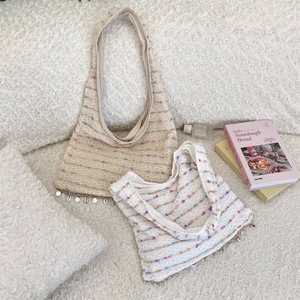 Detail of colorful knitted tote bag with shell charms on a soft plush surface
