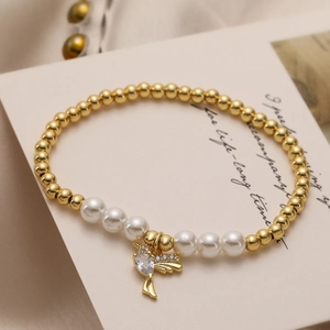 Detail of a gold beaded bracelet with pearls and a sparkling bird charm on an elegant card