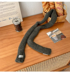 Detailed view of dark green knit scarf texture with a white woven label on wood