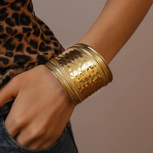 Detailed view of wide gold cuff bracelet featuring hand-hammered ripple texture and bead edges