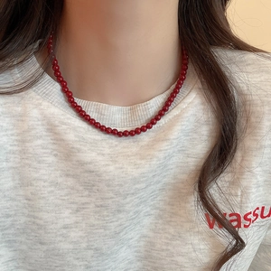 Close-up of vibrant red glass beads necklace worn on neck over a grey t-shirt