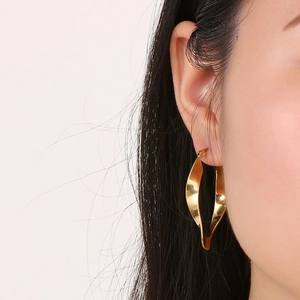 Close-up of a gold U-shaped twisted earring worn by a model in a French vintage style