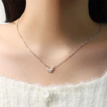 Silver collar necklace with delicate interlaced heart pendant on elegant female model
