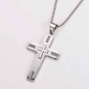 Detail of silver stainless steel cross pendant with Greek Key pattern and relief texture