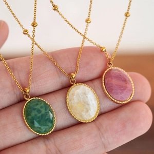 Detailed close-up of faceted natural stone pendants in green and pink on gold chains