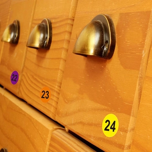 Colorful numbered round stickers showing labels 22 to 24 on a vintage wooden drawer surface