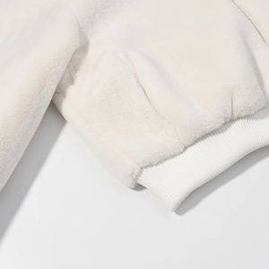 Détail de la veste en fausse fourrure blanche avec poignets en tricot côtelé élastique