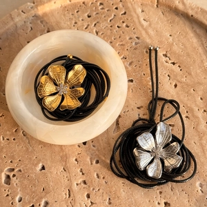 Detailed close-up of 18k gold and silver flower pendants with brushed metal texture