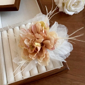 Detail of pink gradient rose hair claw clip with soft feathers in a premium wooden box