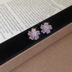 Close-up of pink zircon flower stud earrings on a vintage paper background