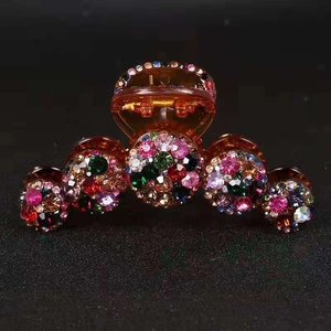 Dettaglio della grande pinza per capelli con strass colorati su base in plastica ambrata