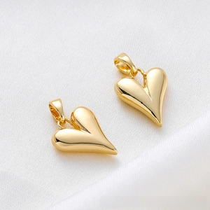Macro detail of 18K gold-plated heart charms with a polished mirror finish on silk
