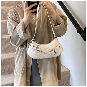Detailed view of white faux leather crescent underarm bag with decorative metal buckles