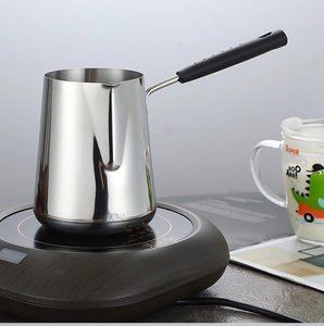 Macro detail of a thick stainless steel milk pot with an ergonomic heat-resistant handle