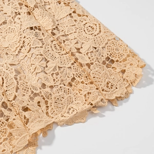 Close-up of beige crochet lace detailing with floral patterns and scalloped edges