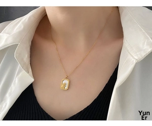 Close-up of a gold rabbit pendant necklace with white shell inlay on a woman