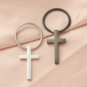 Macro shot of mirror polished stainless steel cross keychains on pink silk fabric