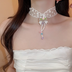 Detail of white lace choker featuring pink floral bow and colorful bead fringe