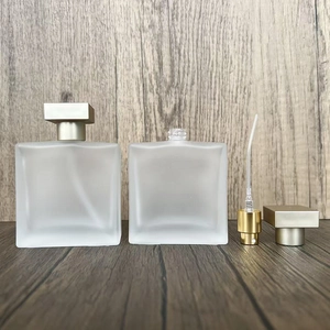 Flat lay of frosted glass perfume bottles with golden spray pumps and square caps