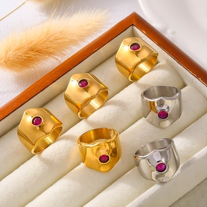 Set of geometric stainless steel open rings with red zircon stones in a jewelry box