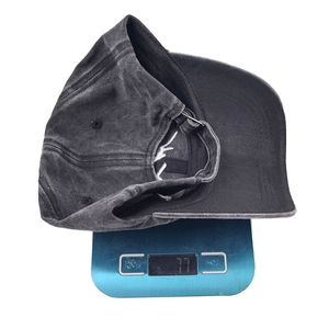 Washed cotton baseball cap in dark grey with embroidery shown on a digital scale 77g