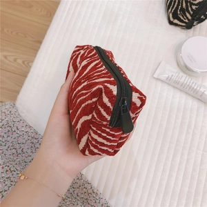 Close-up of red zebra pattern chenille makeup bag held in hand for size detail