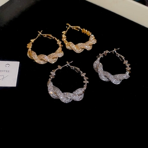 Detail view of twisted gold and silver hoop earrings with shimmering zircons on velvet