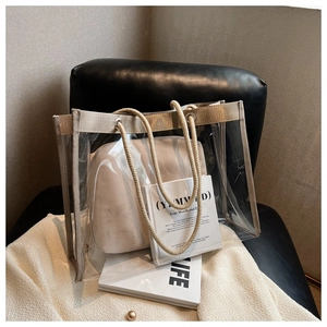 Close-up of a clear PVC tote bag with beige rope handles on a textured chair