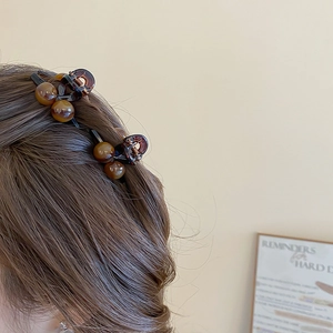 Detailed view of amber acrylic hair clips with yellow beads on long wavy brown hair