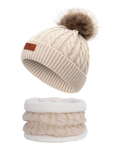 Detail of beige cable knit hat with faux fur pompom and cozy fleece lining texture