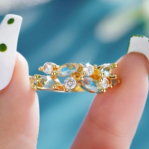 Detailed close-up of leaf-shaped marquise blue gemstones and gold leaf ring band