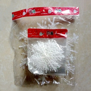 Close-up of white snowflake Christmas tree ornaments in clear packaging with red labels