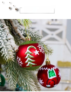 Détail d'une boule de Noël rouge mat avec paillettes vertes et motifs de sapins sur sapin enneigé
