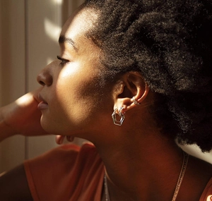 Silver geometric hoop earrings and honeycomb ear cuff set on model with soft lighting
