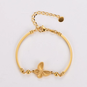Detailed macro view of gold butterfly bracelet with intricate wing textures and heart charm