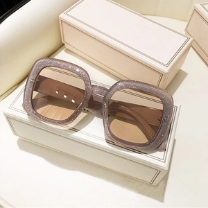 Detail of square oversized glitter frame sunglasses with brown lenses and wide temples