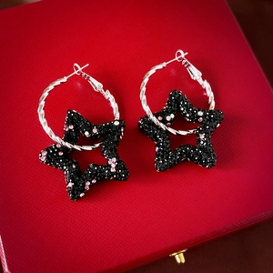 Close-up of star hoop earrings with black and pink rhinestones on a red gift box