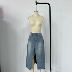Detail of light blue washed denim skirt featuring raw edges and a high front slit